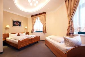 two beds in a room with two windows at Hotel Europäischer Hof in Elsterwerda +6 photos