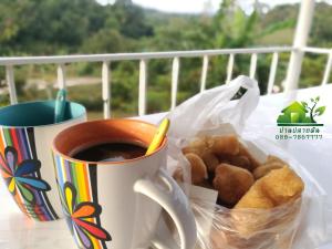 a cup of coffee and a bag of pastries on a table at บ้านปลายฝัน Baanplaifun in Ban Huai Phai