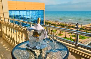 a table with two wine glasses on a balcony with the ocean at Ribera Resort&SPA in Yevpatoriya