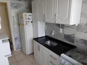 Una cocina con fregadero y refrigerador blanco. en Capao da canoa Apto. 3 dorm, en Capão da Canoa
