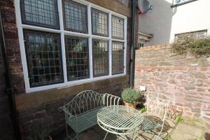 una mesa y sillas junto a una pared de ladrillo en The Old Reading Rooms en Wiveliscombe