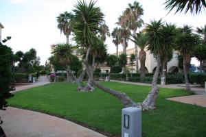 a sign in a park with palm trees and a building at Makronisos Village in Ayia Napa