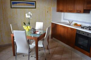 a kitchen with a table with white chairs and a sink at Appartamento panoramico in Pancole