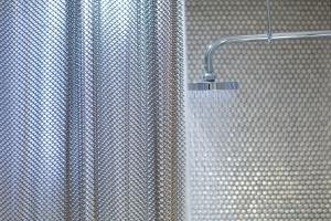 a shower with a metal curtain in a bathroom at Dream Downtown, by Hyatt in New York