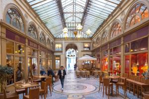 a mall with tables and chairs and a glass ceiling at Hôtel Odyssey in Paris