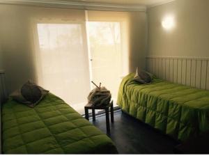 a bedroom with two green beds and a window at Apartamentos Nevados de Pucón in Pucón