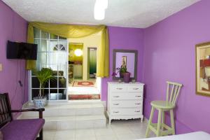 a purple room with a bed and a dresser and a window at Orchid Cottage in Kingston