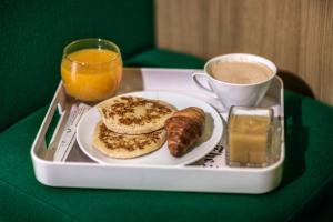 a tray with a plate of breakfast food and a cup of coffee at Hôtel Odyssey by Elegancia in Paris