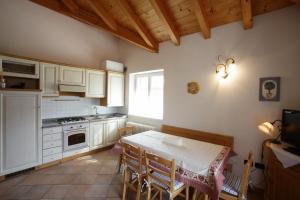 una cocina con mesa y sillas y una cocina con armarios blancos. en Casa Rubino Lake & Dolomites, en Molveno