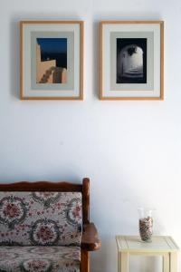 two framed pictures on a white wall with a bed and a table at Hotel Paros in Parikia