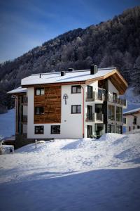 a building in the snow in front of a mountain at Engadin Lodge PREMIUM & PRIVATE in Samnaun