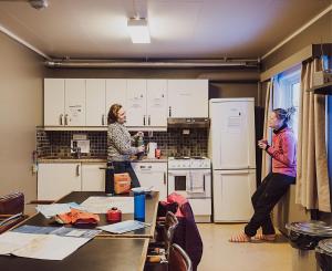 a woman standing in a kitchen next to a child at Coal Miners’ Cabins in Longyearbyen