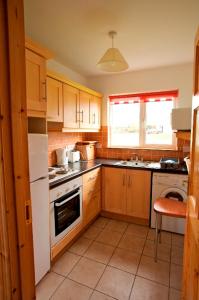 a kitchen with wooden cabinets and a white refrigerator at Burren Way Cottages in Ballyvaughan