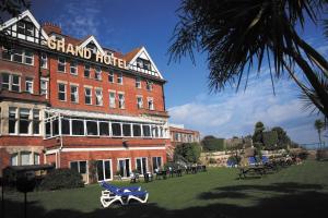 スワネージにあるGrand Hotel Swanageのレンガ造りの大きな建物で、その前にピクニックテーブルがあります。