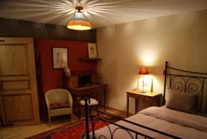um quarto com uma cama, uma secretária e um candeeiro em Gîte du Thalala em Bernardvillé