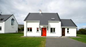 une maison blanche avec une porte rouge dans l'établissement Burren Way Cottages, à Ballyvaughan