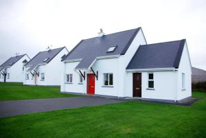 una fila di case bianche con una porta rossa di Burren Way Cottages a Ballyvaughan
