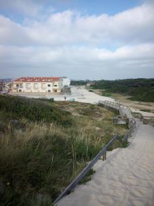 una pasarela que conduce a una playa con un edificio en The Beach House en Figueira da Foz