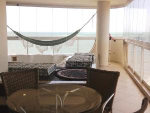 a room with a table and chairs and a hammock at Edificio Estrela Dourada in Itapema