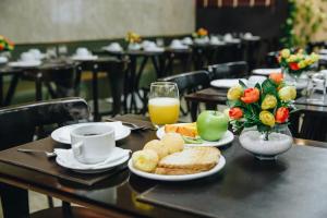 a table with plates of food and a cup of orange juice at Athus Brasilia Hotel by Bsb Inn in Brasília +60 photos