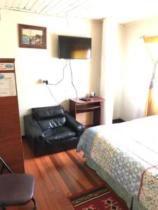 a hotel room with a bed and a leather chair at Hospedaje Freire in Osorno
