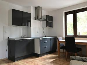 una cocina con armarios en blanco y negro y una mesa en Nowa Apartamenty Apartament Słoneczny Bulwar, en Krynica Morska