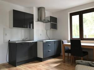 a kitchen with black and white cabinets and a table at Nowa Apartamenty Apartament Słoneczny Bulwar in Krynica Morska