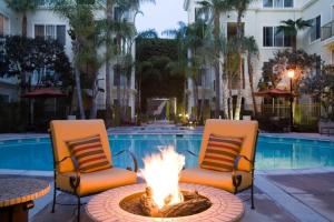 Marina Del Rey's Grand 2/2 Suite Pool View في لوس أنجلوس: كرسيين ومدفأة امام المسبح