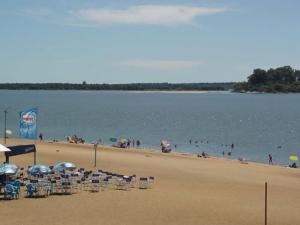 a beach with chairs and umbrellas and people in the water at Complejo El Chaparral in Colón