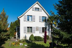 una casa bianca con un albero di fronte di B&B Kalimera Pratteln a Pratteln