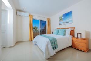 a white bedroom with a bed and a window at Isla Mazatlan Residence Club in Mazatlán