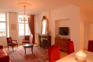 a living room with a table and chairs and a television at Residence des Bains in Plombières-les-Bains