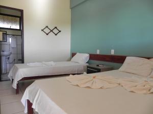 a room with two beds with white sheets at Pousada Doce Rio in Três Marias