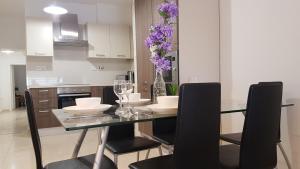 una cucina con tavolo in vetro, sedie e fiori viola di Spinola Seafront Apartment a San Giuliano