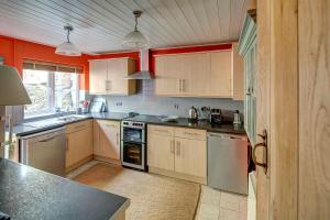 a kitchen with wooden cabinets and a black counter top at Aberdaron Cottage 2 Bryn Chwilog in Aberdaron