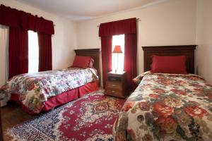 two beds in a bedroom with red curtains at Village Suites in Margaretville