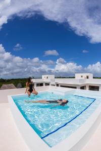 a person is in the water with a surfboard at Intima Resort Tulum Adults Only (Clothing Optional) in Tulum