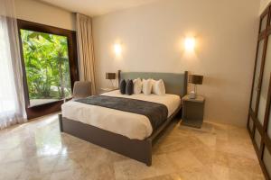 a bedroom with a large bed and a large window at Intima Resort Tulum Adults Only (Clothing Optional) in Tulum