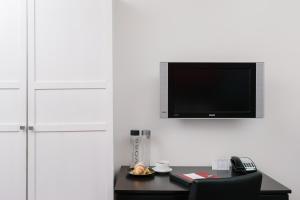 um quarto com uma secretária e uma televisão na parede em Moda Hotel em Vancouver