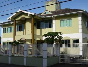 żółty dom z białym płotem przed nim w obiekcie Pousada 4 Estações Campeche w mieście Florianópolis