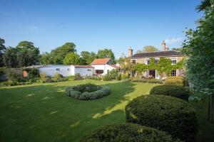 ein großer Hof mit einem Haus und einigen Büschen in der Unterkunft Vicarage House & Pool House in Hockham