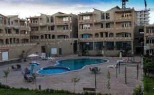 een groot appartementencomplex met een zwembad ervoor bij Complexe Touristique BouZour in Mostaganem