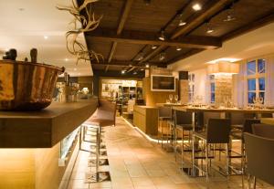 a restaurant with a bar with chairs and tables at Hotel Resch in Kitzbühel