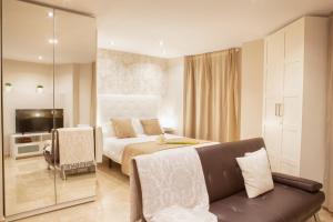 une chambre avec un lit, un canapé et une télévision dans l'établissement Apartamentos Boutique Salamanca, à Salamanque