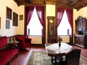 ein Wohnzimmer mit roten Stühlen, einem Tisch und einer Uhr in der Unterkunft Zamek Usobi in Úsobí