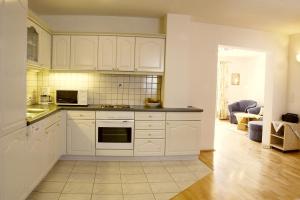 a kitchen with white cabinets and a living room at Landhaus am Golfplatz in Seefeld in Tirol