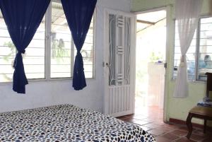 a bedroom with a bed with blue curtains and a door at Descanso en el Campo in Cali