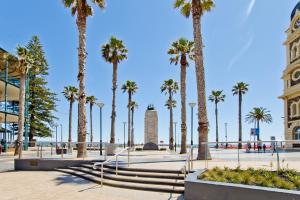 a group of palm trees in a plaza next to the beach at Glenelg Oasis Studios in Adelaide