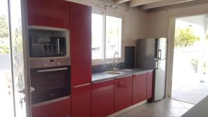 cocina con armarios rojos, fregadero y nevera en Villa Taho, en Terre-de-Haut