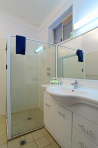 a white bathroom with a sink and a shower at Rest Point Motor Inn in Glen Innes